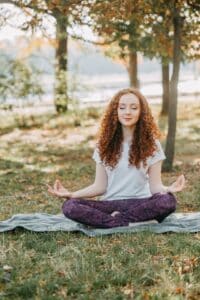 Who is Freya? photo of red headed woman meditating outdoors.