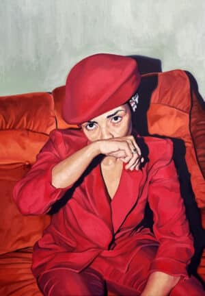 original oil portrait - woman wearing bright red suit and hat sitting on an orange sofa, with her hand covering the bottom half of her face.