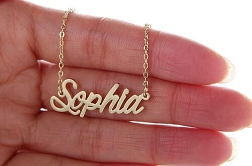 A handing holding a necklace with the name Sophia as a pendant.<br />
