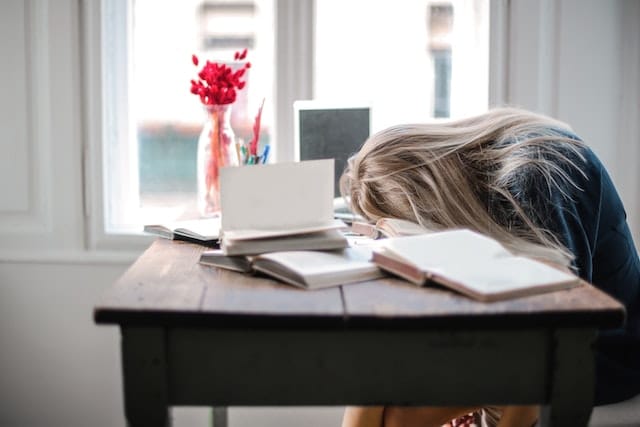 Photo of a woman with her head face down resting on a desk.