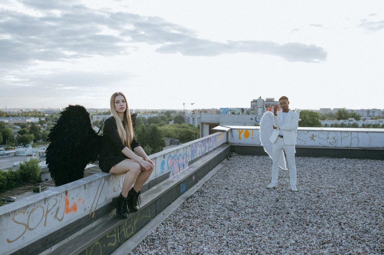 A woman dressed as a black angel and a man dressed as a white angel on a rooftop.
