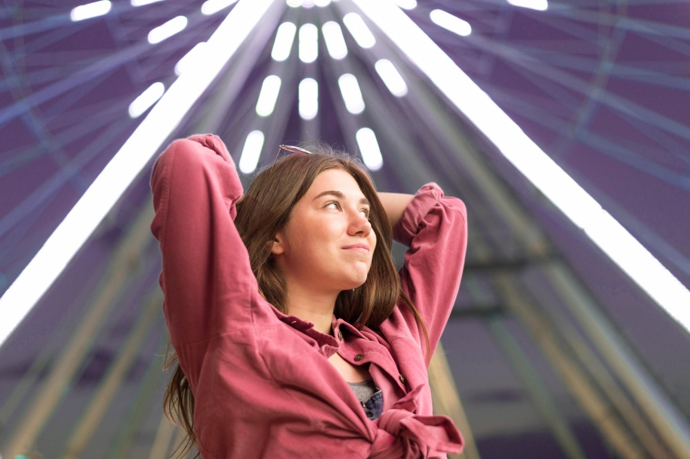 Transcendence: woman reaching to the sky in front of an illuminated shaft.