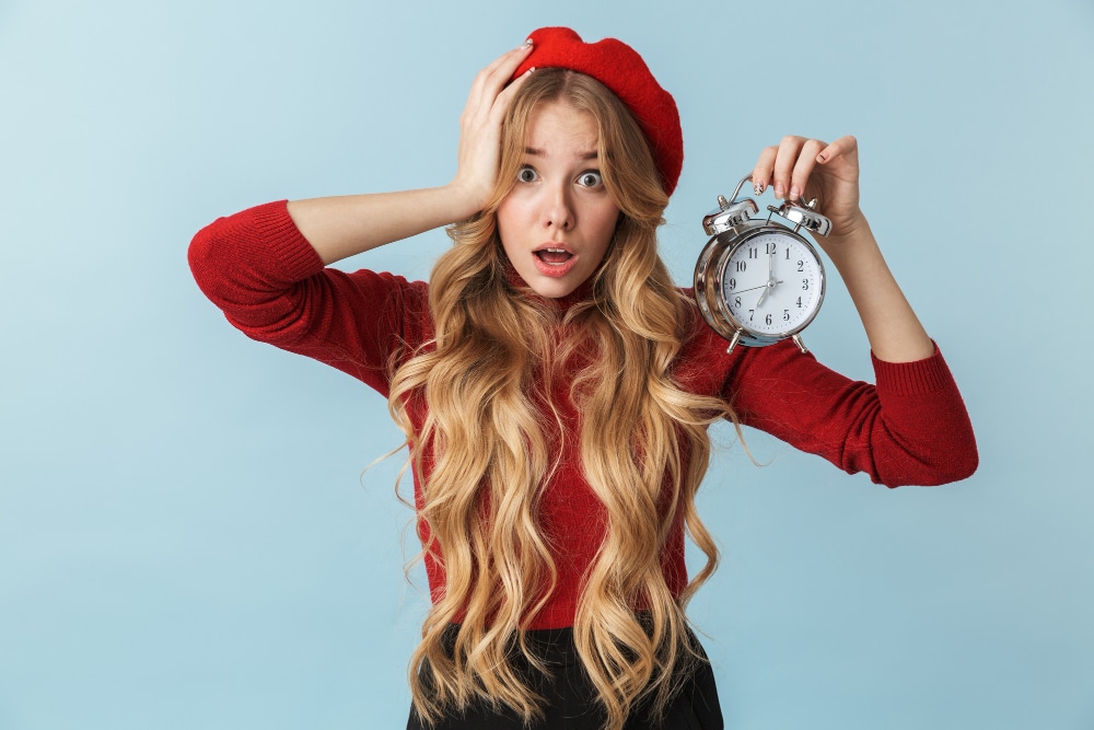 How long does a spiritual awakening take? Young woman holding an alarm clock.