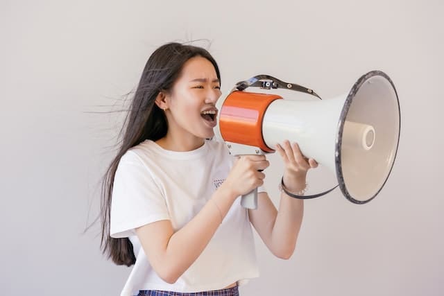 Young woman shouting through a megaphone.