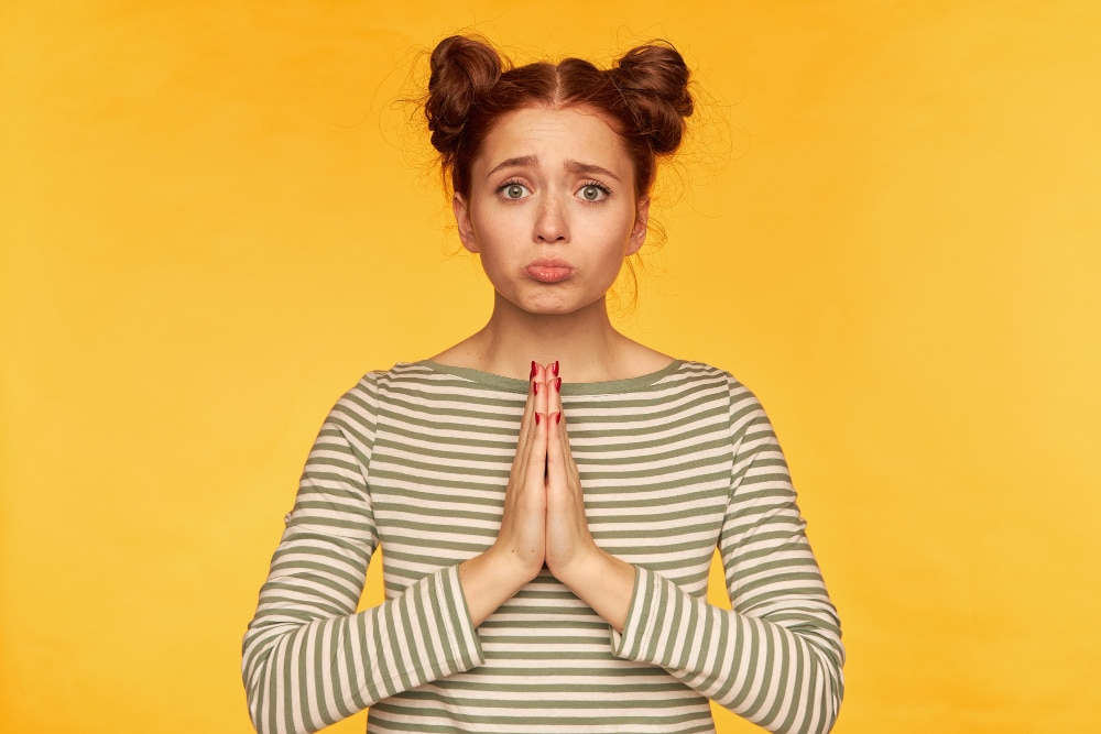 Spiritual awakening top 5 mistakes: young woman with prayer hands and a troubled expression.