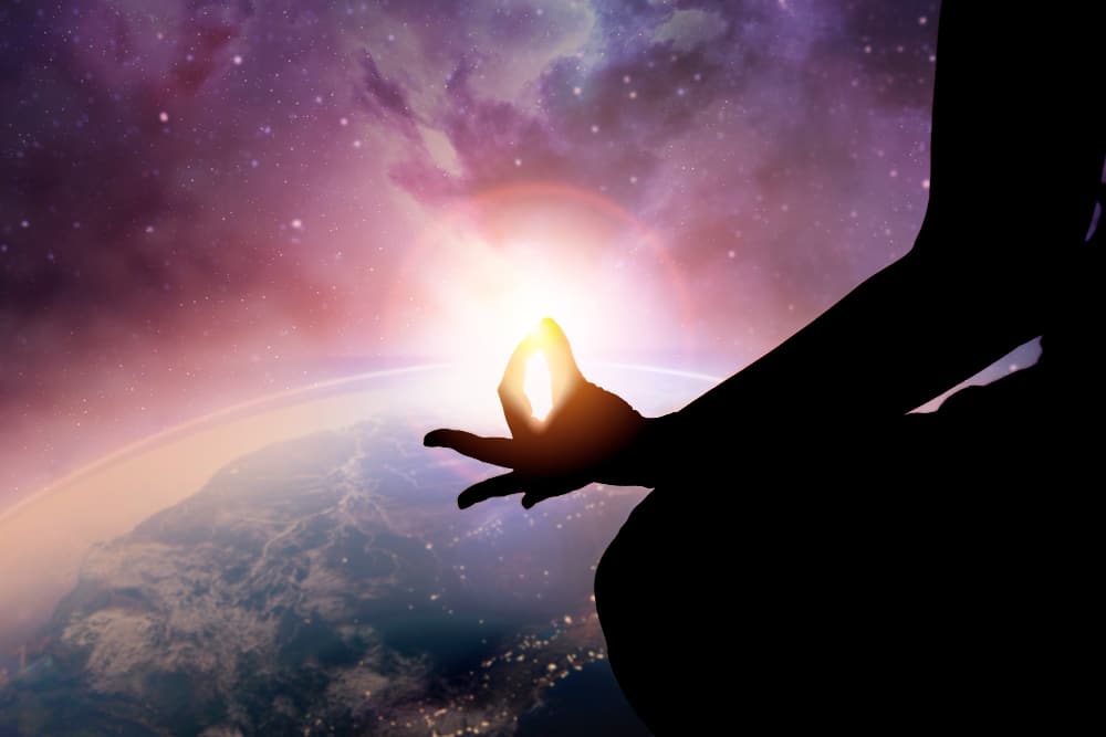 Spiritual universe: silhouette of a person meditating against a backdrop of the universe.