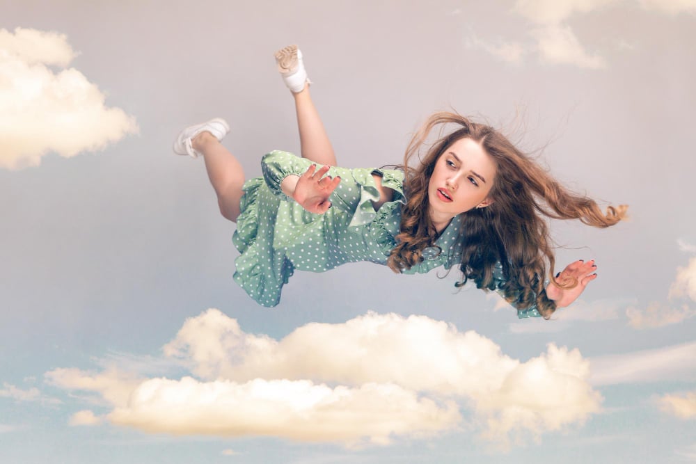 What does flying in a dream mean spiritually? Young woman flying above a cloud.